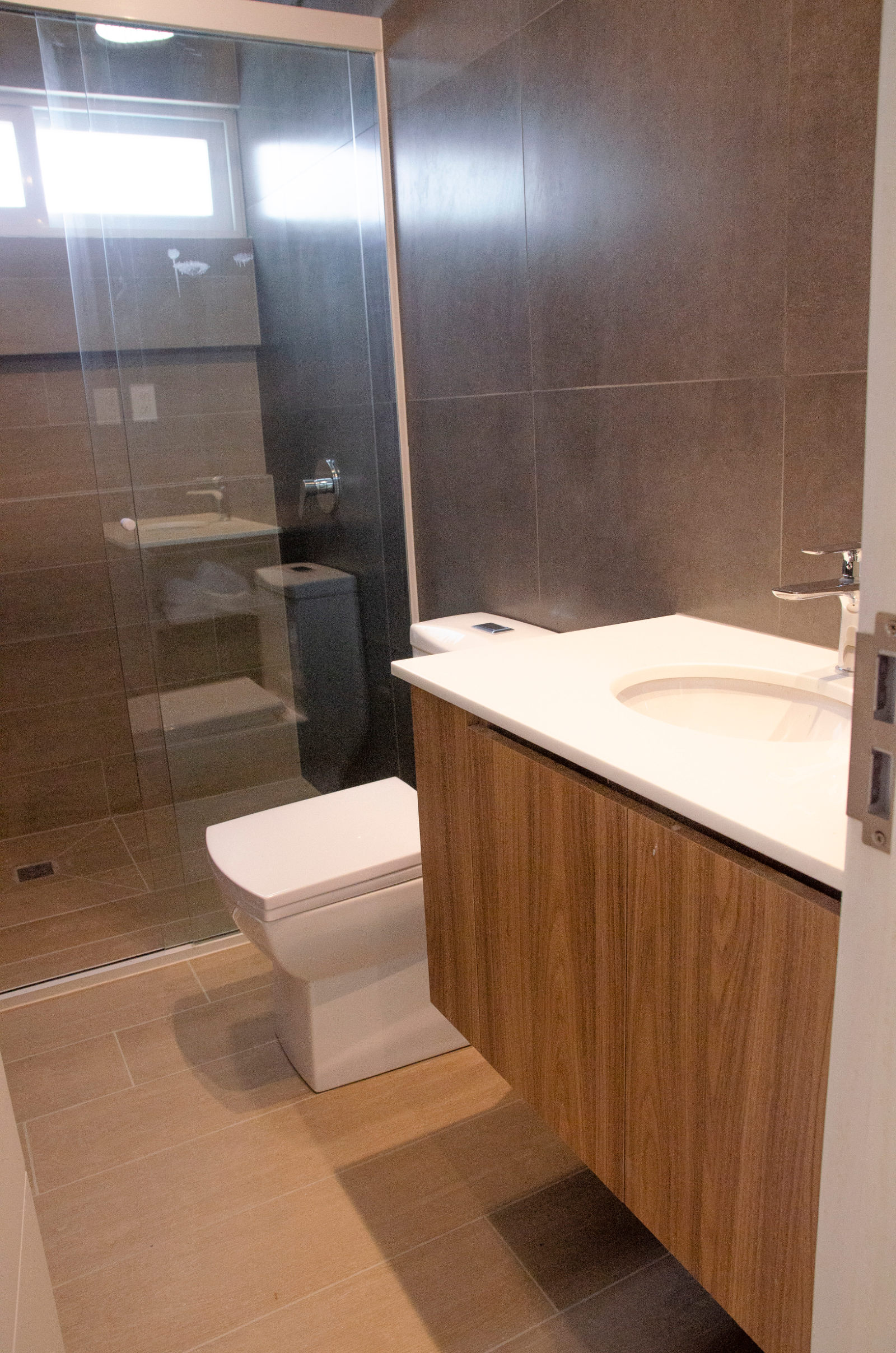 Baño del departamento modelo, con revestimiento de piso a techo y mueble inferior