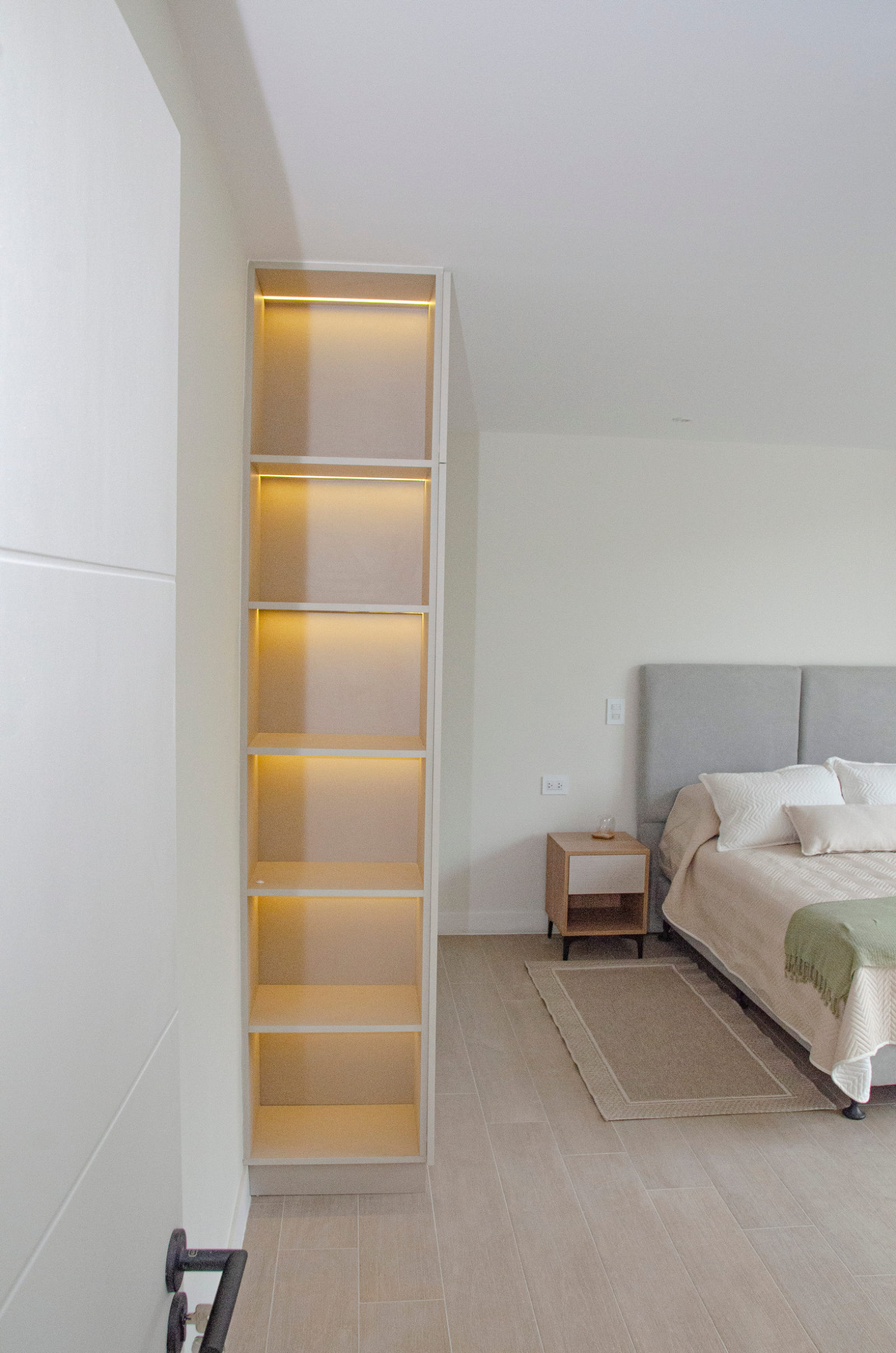 Ropero empotrado con estantería iluminada, junto al dormitorio